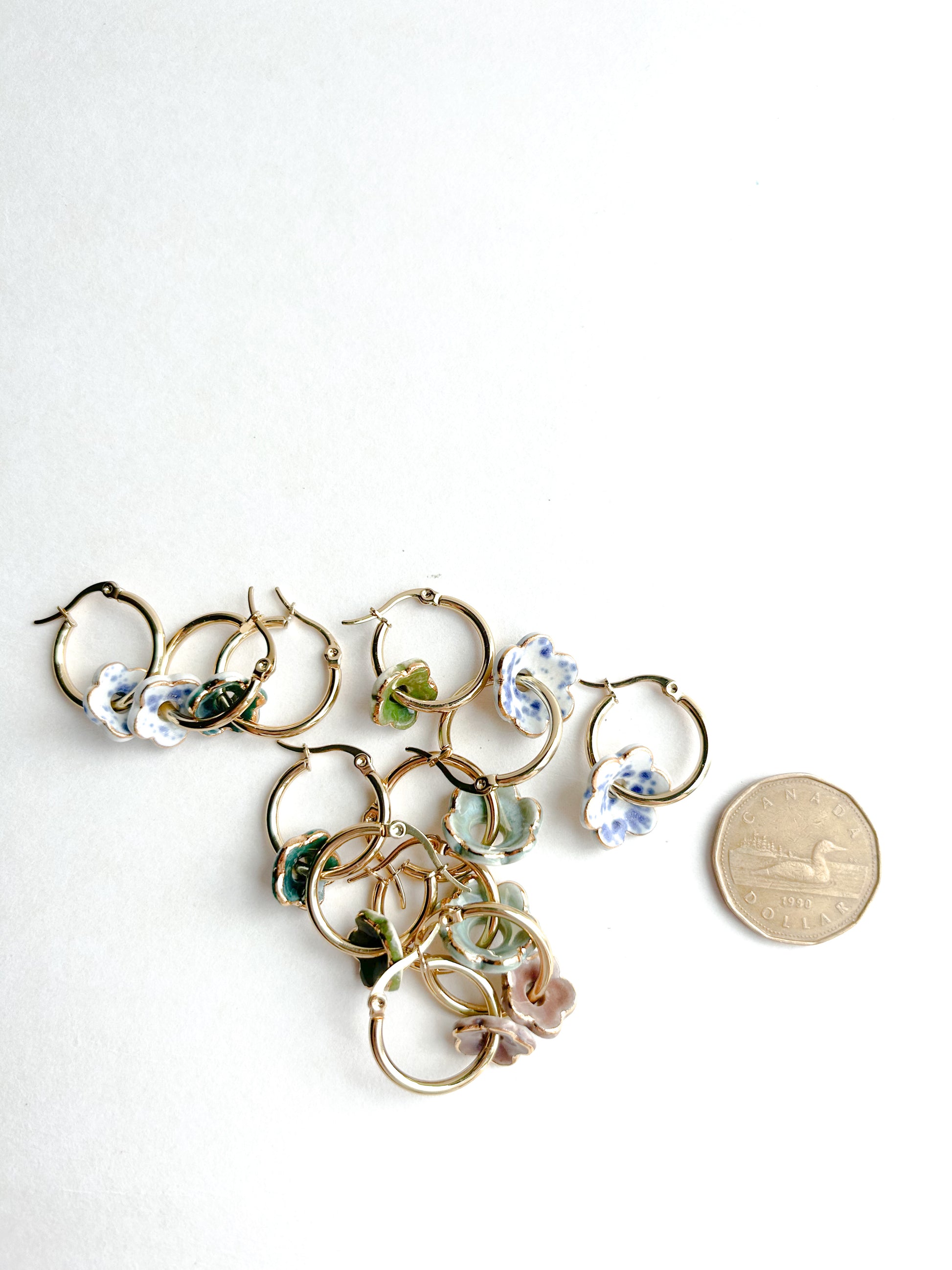 Gold hoop earrings with floral designs on a white background, next to a coin for scale.