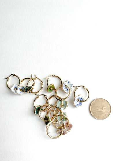 Gold hoop earrings with floral designs on a white background, next to a coin for scale.